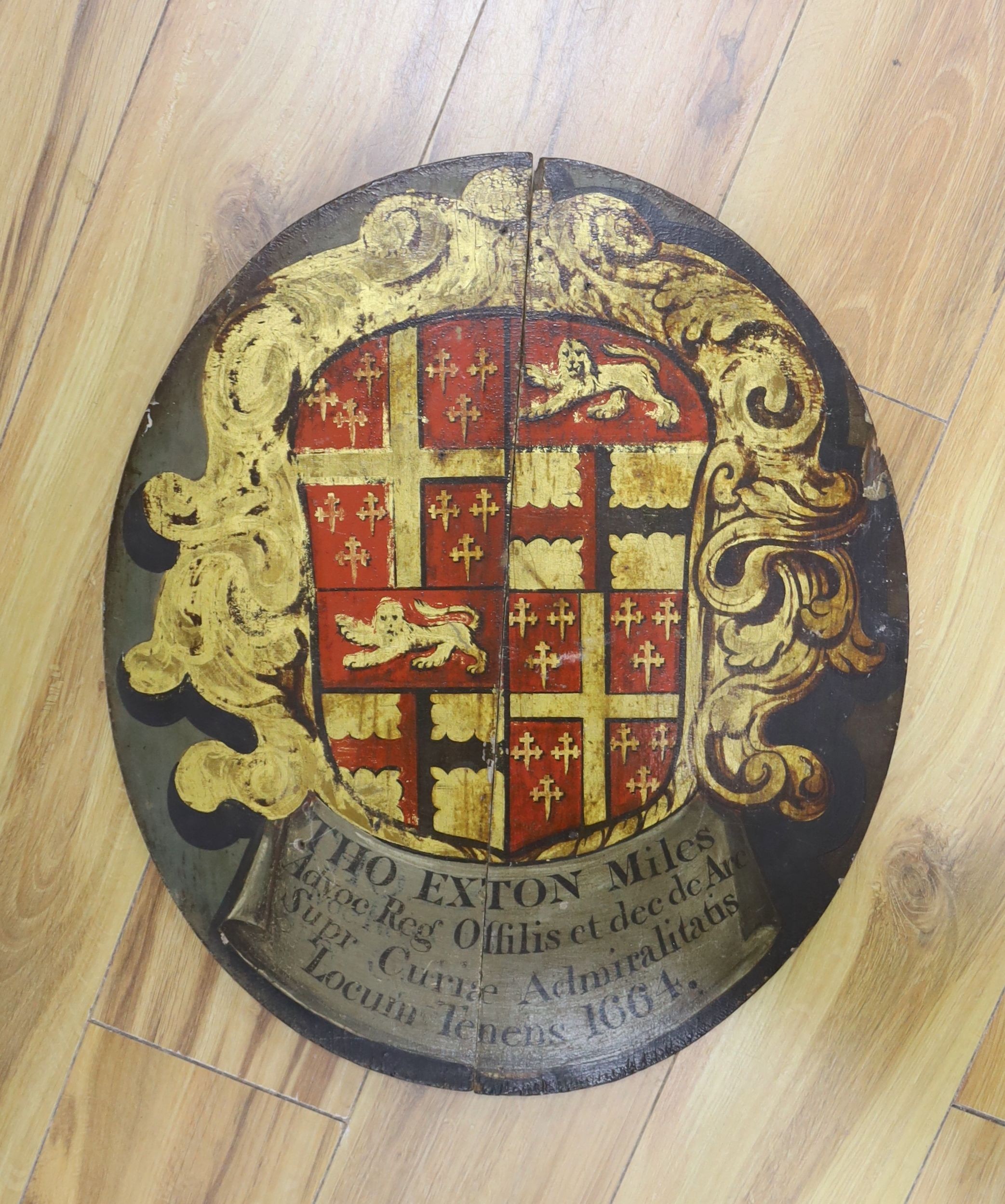 An oval painted wood armorial panel, for Admiral Thomas Exton, inscribed 1664 and possibly of the period, 52cm